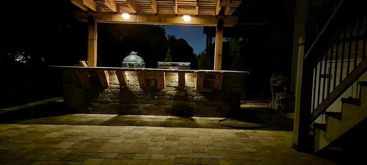 Outdoor kitchen under a covered patio lit up at night