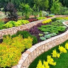 Curved stone retaining wall with layered garden plantings